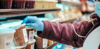 Osoba w supermarkecie sięga po gotowy produkt z etykietą