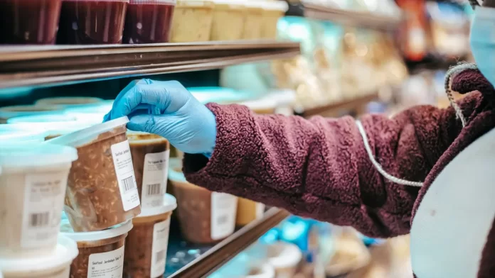 sprawdzanie-skladu-alergia-pokarmowa Osoba w supermarkecie sięga po gotowy produkt z etykietą